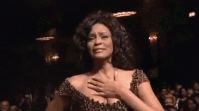 A Woman Is Dancing In Front Of A Crowd In A Dark Room . GIF