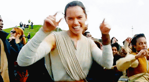 A Woman Is Dancing In Front Of A Crowd Of People While Giving A Thumbs Up . GIF