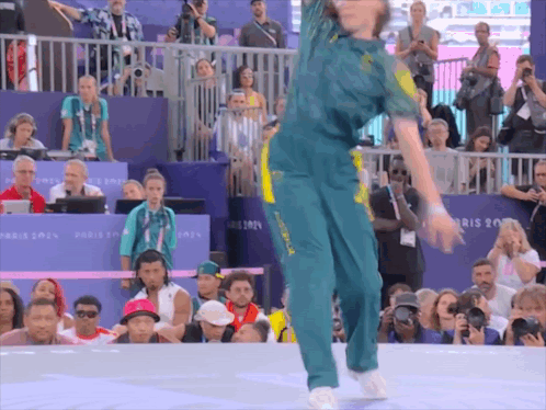 A Woman Is Dancing In Front Of A Crowd With A Sign That Says Paris 2014 GIF