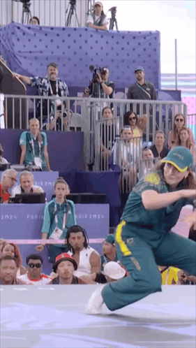 A Woman Is Dancing In Front Of A Crowd With A Sign That Says Paris 2021 On It GIF
