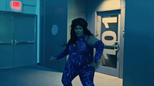 A Woman Is Dancing In Front Of A Door With The Number 101 On It GIF