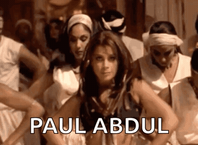 A Woman Is Dancing In Front Of A Group Of People And The Name Paul Abdul Is On The Bottom GIF