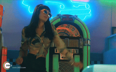 A Woman Is Dancing In Front Of A Jukebox That Says Zees On It GIF