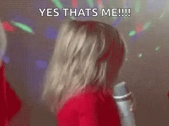 A Woman Is Dancing In Front Of A Microphone With The Words `` Yes Thats Me '' Written On Her Face . GIF
