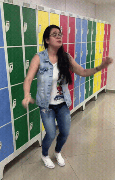 A Woman Is Dancing In Front Of A Row Of Lockers GIF