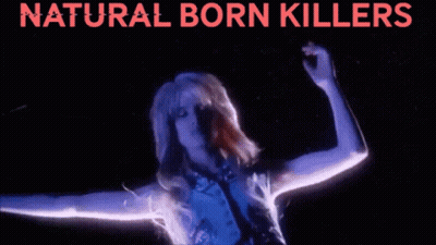 A Woman Is Dancing In Front Of A Sign That Says Natural Born Killerss GIF