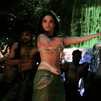 A Woman Is Dancing In Front Of A Waterfall In A Green Light GIF