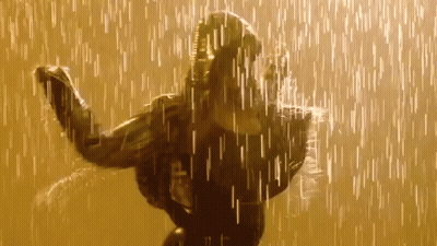 A Woman Is Dancing In The Rain While Wearing A Black Jacket . GIF