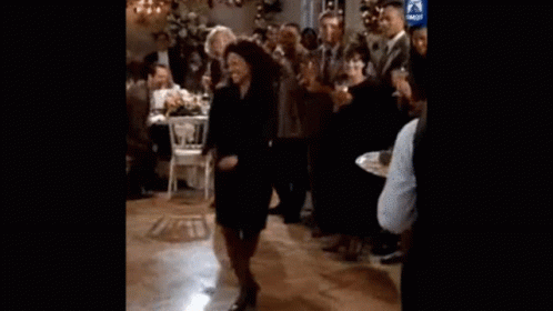 A Woman Is Dancing On A Dance Floor In Front Of A Crowd At A Party . GIF