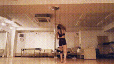 A Woman Is Dancing On A Pole In A Room GIF