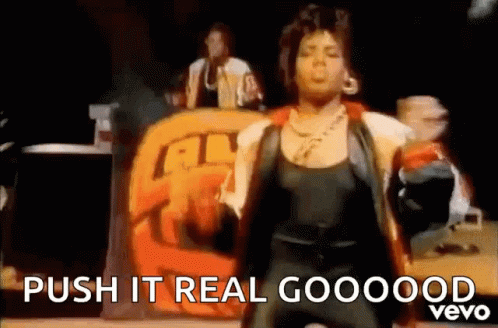 A Woman Is Dancing On A Stage In Front Of A Sign That Says Push It Real Goooood Vevo . GIF