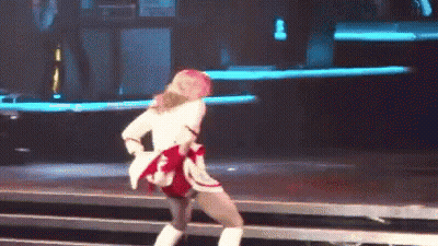 A Woman Is Dancing On A Stage Wearing A White Jacket And Boots . GIF
