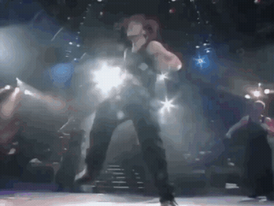 A Woman Is Dancing On A Stage With A Blurred Background GIF
