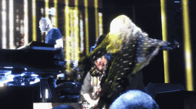 A Woman Is Dancing On A Stage With A Man Playing A Piano Behind Her GIF