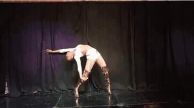 A Woman Is Dancing On A Stage With A Purple Curtain In The Background . GIF