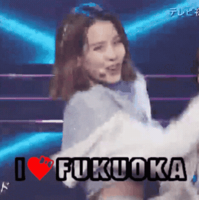 A Woman Is Dancing On A Stage With The Words I Love Fukuoka Written Above Her GIF