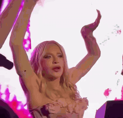A Woman Is Dancing With Her Arms In The Air . GIF