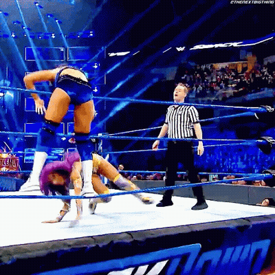 A Woman Is Doing A Handstand In A Wrestling Ring With A Referee Watching . GIF