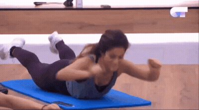 A Woman Is Doing Exercises On A Blue Mat On A TV Show GIF