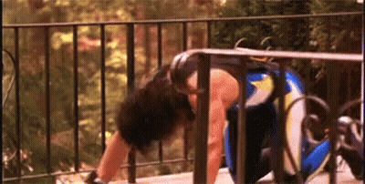 A Woman Is Doing Push Ups On A Balcony Next To A Fence . GIF