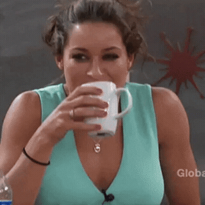A Woman Is Drinking A Cup Of Coffee With A Globe Logo In The Background GIF