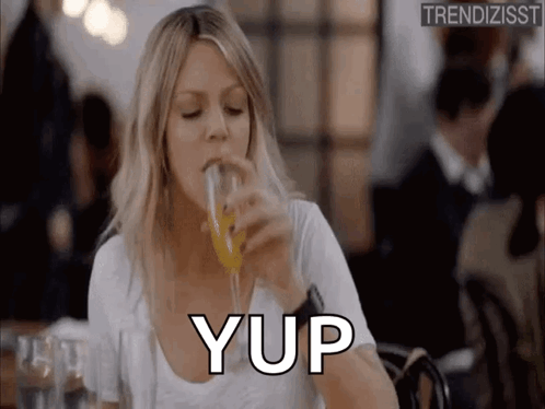 A Woman Is Drinking A Glass Of Orange Juice In A Restaurant And Saying Yup . GIF