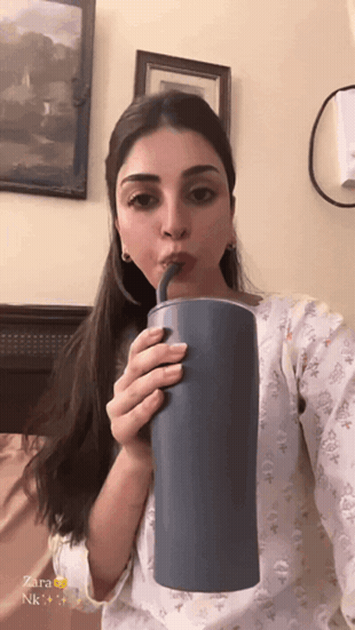 A Woman Is Drinking From A Blue Cup With A Straw And The Name Zara Is On The Bottom GIF