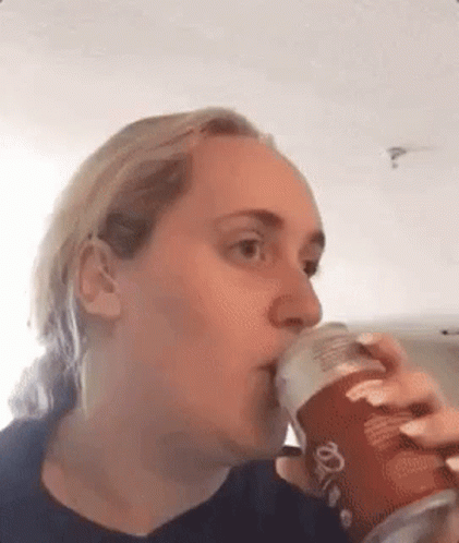A Woman Is Drinking From A Can Of Pringles . GIF