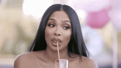 A Woman Is Drinking From A Glass With A Straw . GIF