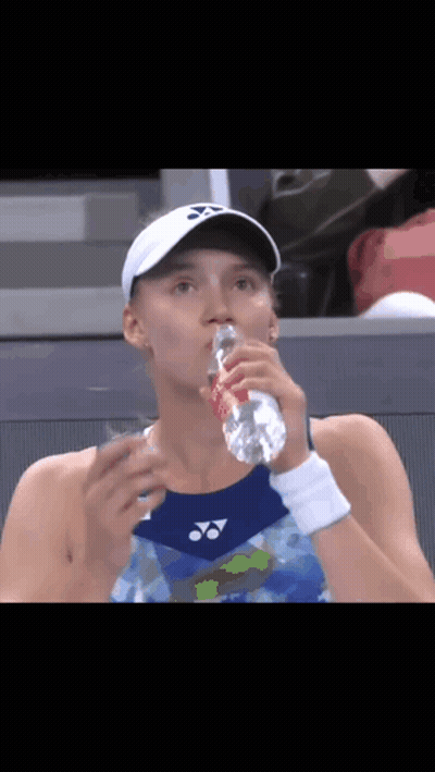 A Woman Is Drinking Water From A Bottle While Wearing A White Hat . GIF