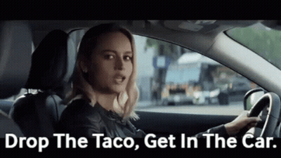 A Woman Is Driving A Car And Saying `` Drop The Taco , Get In The Car '' . GIF