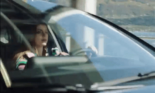 A Woman Is Driving A Car On A Highway . GIF