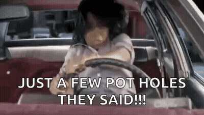 A Woman Is Driving A Car With The Words `` Just A Few Pot Holes They Said '' Written On The Screen . GIF