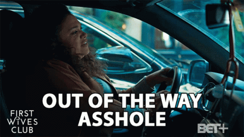 A Woman Is Driving A Car With The Words Out Of The Way Asshole On The Screen GIF