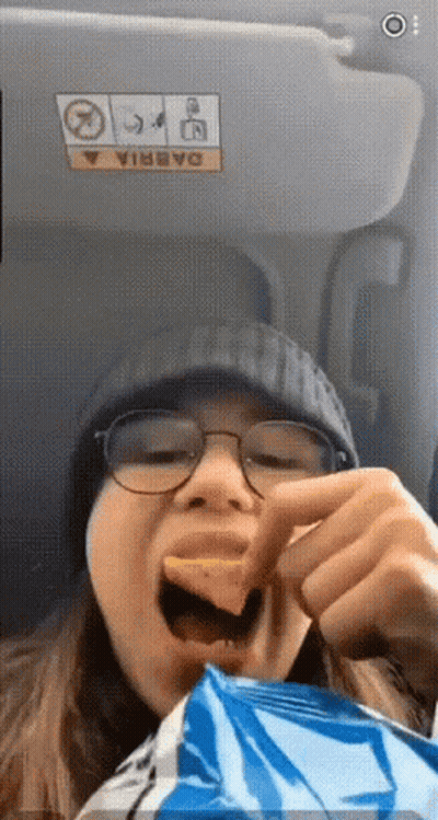 A Woman Is Eating A Bag Of Chips In A Car GIF