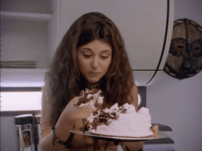 A Woman Is Eating A Cake With Whipped Cream On Top GIF