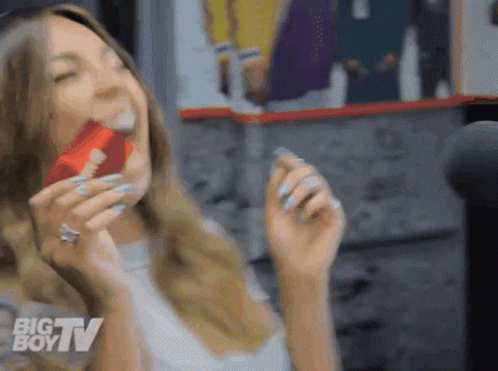 A Woman Is Eating A Candy Bar With The Big Boy Tv Logo In The Background GIF