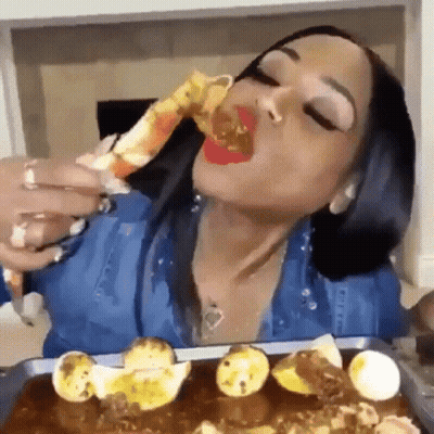 A Woman Is Eating A Crab Leg With A Spoon . GIF