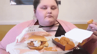 A Woman Is Eating A Hamburger And Chicken Nuggets From A Box GIF