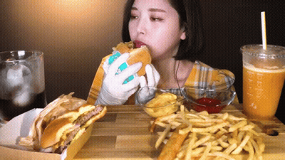 A Woman Is Eating A Hamburger And French Fries At A Table With A Drink That Says Bubble Tea GIF