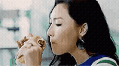 A Woman Is Eating A Hamburger In A Restaurant . GIF