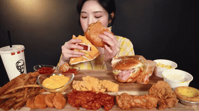 A Woman Is Eating A Hamburger With A Kfc Drink GIF