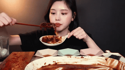 A Woman Is Eating A Large Plate Of Food With A Spoon GIF