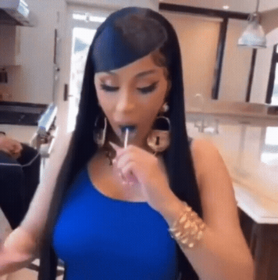 A Woman Is Eating A Lollipop In A Kitchen . GIF