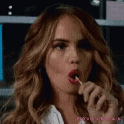 A Woman Is Eating A Lollipop With Red Lipstick On Her Lips . GIF
