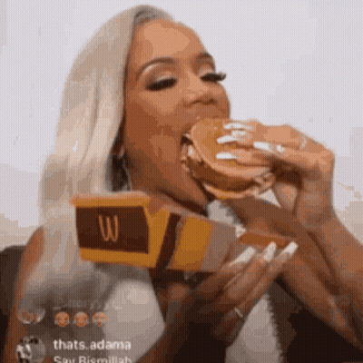 A Woman Is Eating A Mcdonald 'S Hamburger While Holding A Box Of Mcdonald 'S . GIF