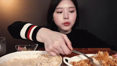 A Woman Is Eating A Plate Of Food With A Fork GIF