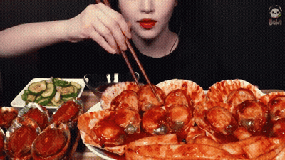 A Woman Is Eating A Plate Of Food With Chopsticks . GIF