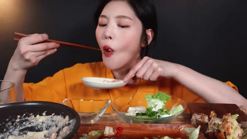 A Woman Is Eating A Salad With Chopsticks And A Bowl Of Salad . GIF