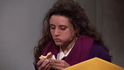 A Woman Is Eating A Sandwich While Holding A Folder . GIF